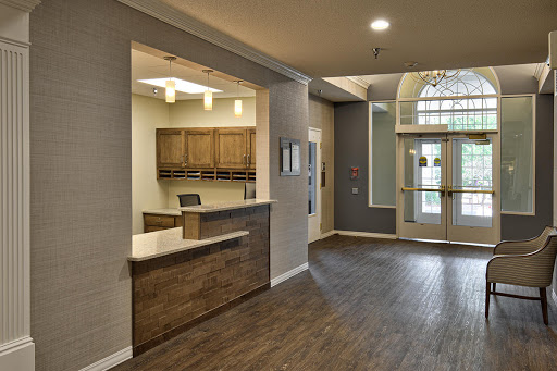 A modern lobby featuring a reception desk and wooden cabinetry, illuminated by soft lighting.