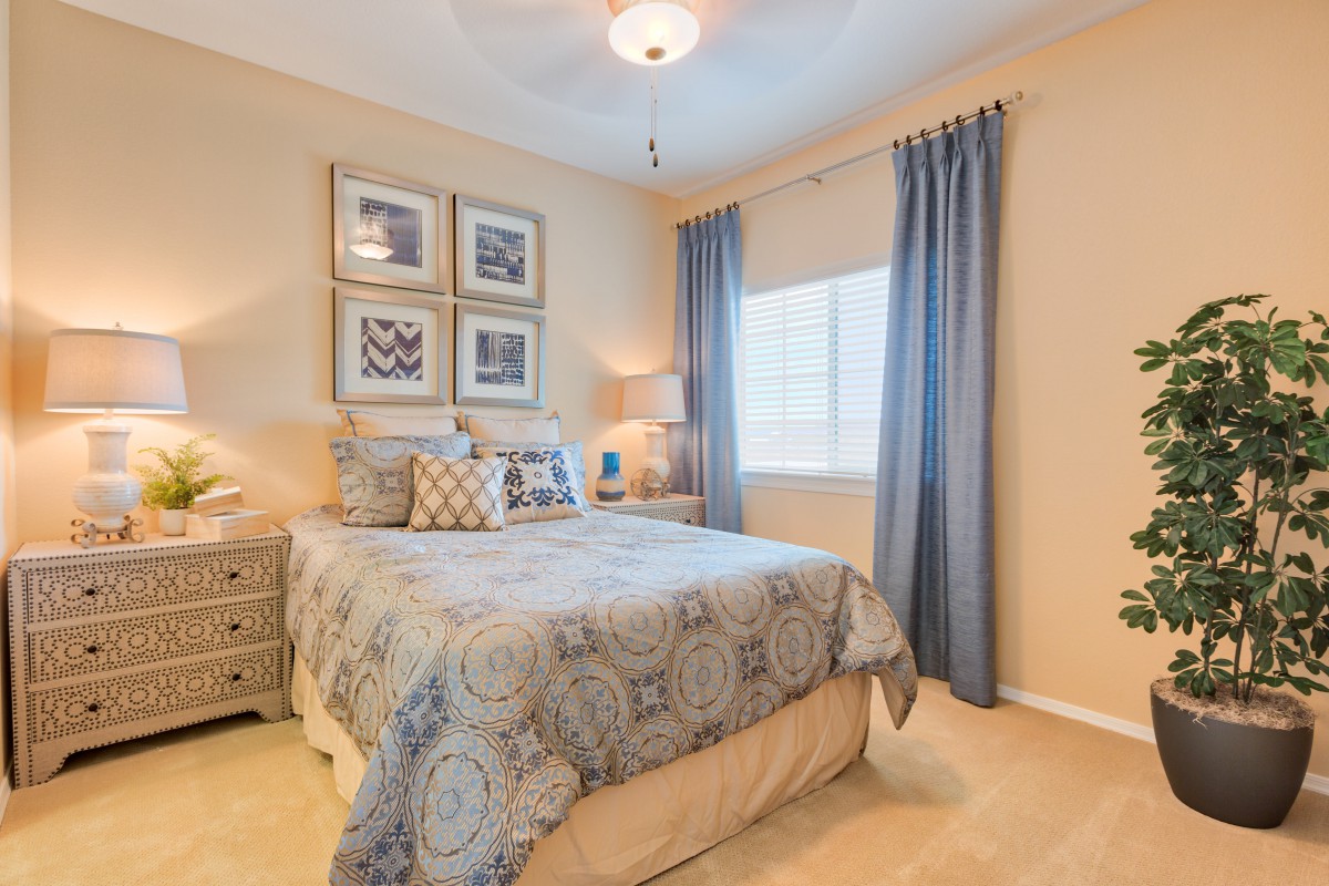 A cozy bedroom with a neatly made bed, decorated with patterned pillows and artwork on the walls.