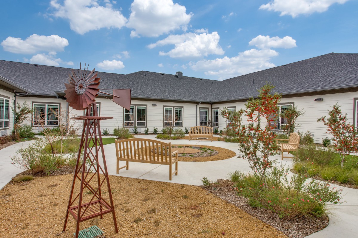 A serene courtyard with benches and a decorative windmill surrounded by landscaped gardens.
