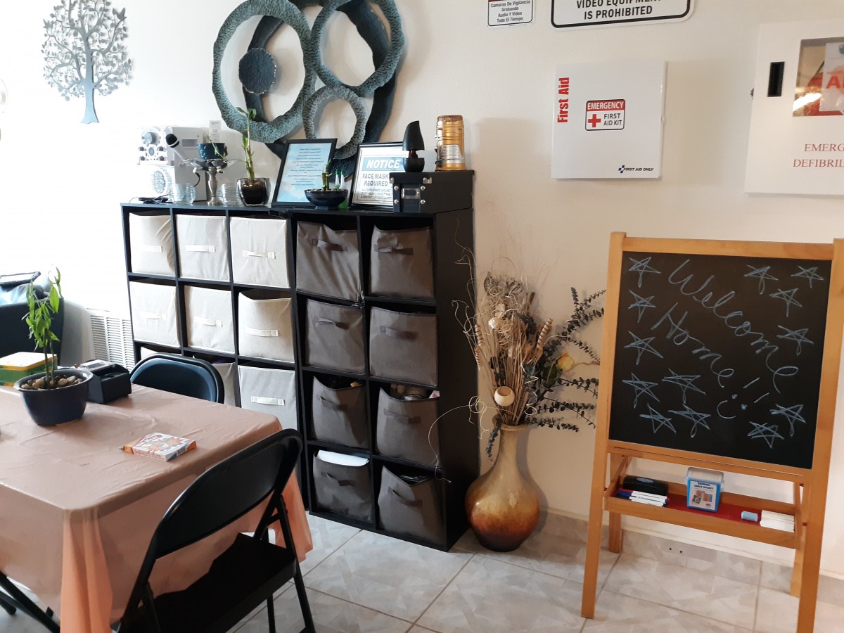 A cozy living space featuring shelving units with storage cubes, decorative art pieces, a chalkboard, and a table.