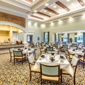 A spacious and elegantly decorated dining room with multiple set tables ready for guests.