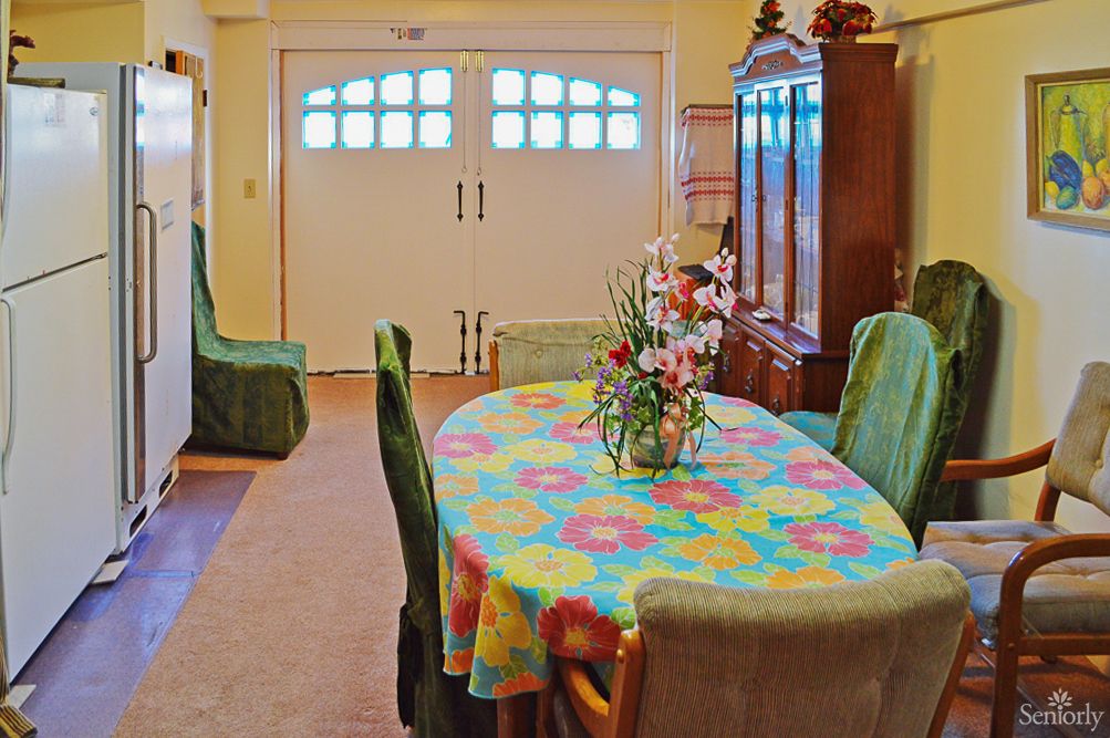 A cozy dining room with a colorful tablecloth and a floral arrangement on the table.