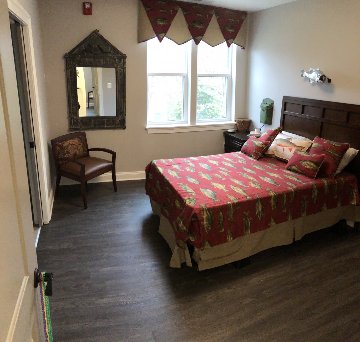 A cozy bedroom with warm decor, featuring a bed, chair, and a large window.