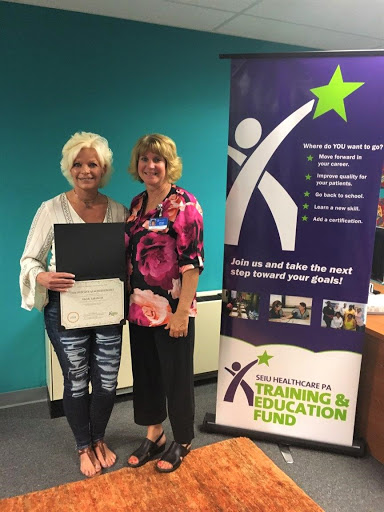 Two women proudly displaying a certification at a training and education event.