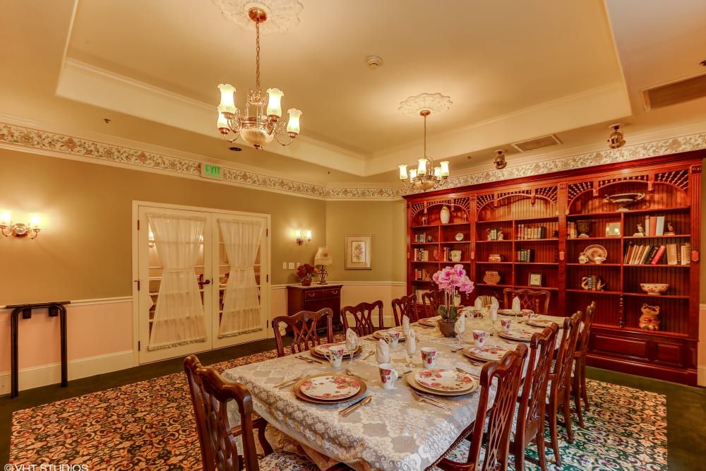 A traditional dining room with an elegantly set table and a large bookshelf.