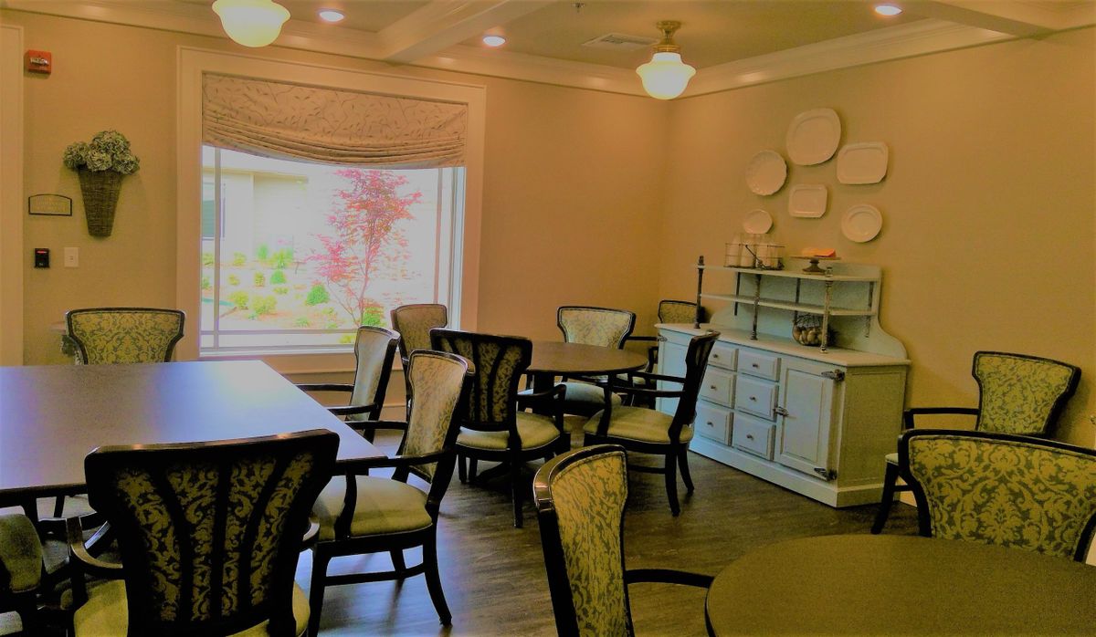 A cozy dining room featuring elegant tables and chairs, with a large window providing natural light.