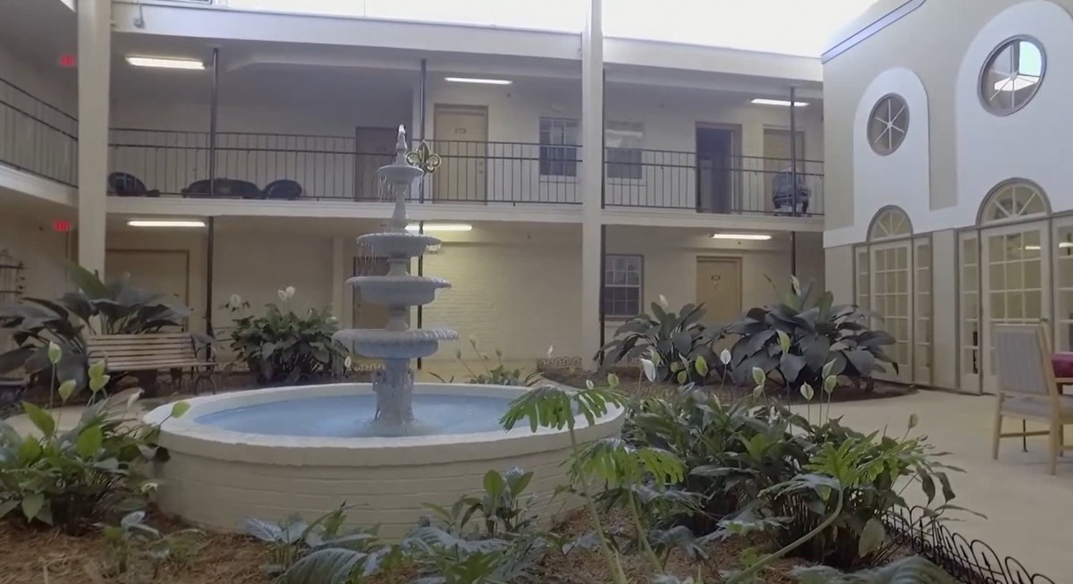 A courtyard with a multi-tiered fountain surrounded by plants and apartment balconies.