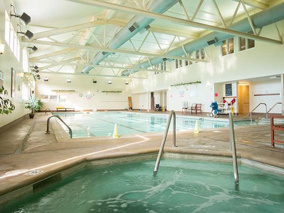 A spacious indoor swimming pool area with a jacuzzi in the foreground, offering facilities for relaxation and recreation.