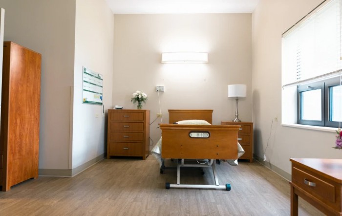 A clean and simple hospital room with a single bed and minimal furnishings.