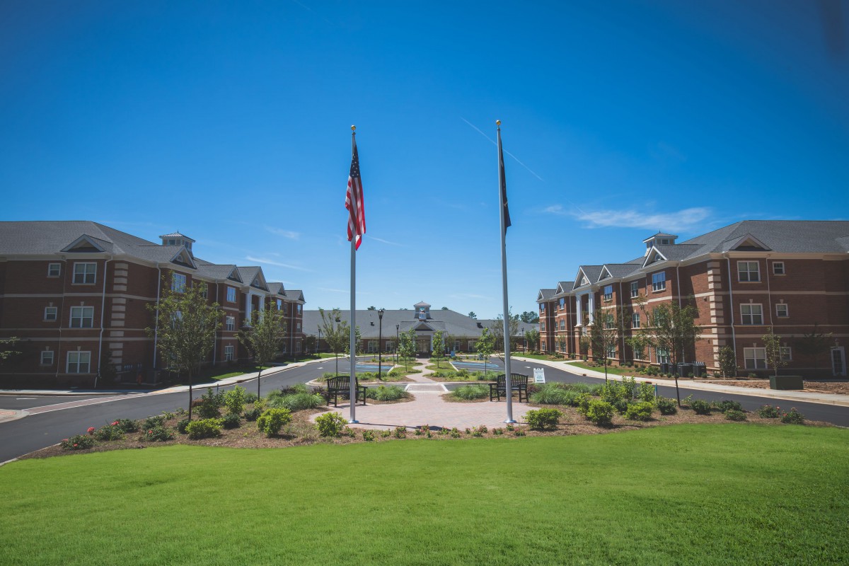 A well-maintained campus with flags, buildings, and a central pathway under a clear blue sky.