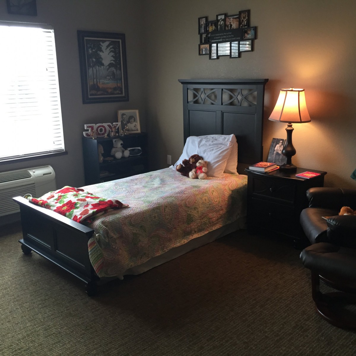 A cozy bedroom with a single bed, nightstand, and warm lighting from a lamp.