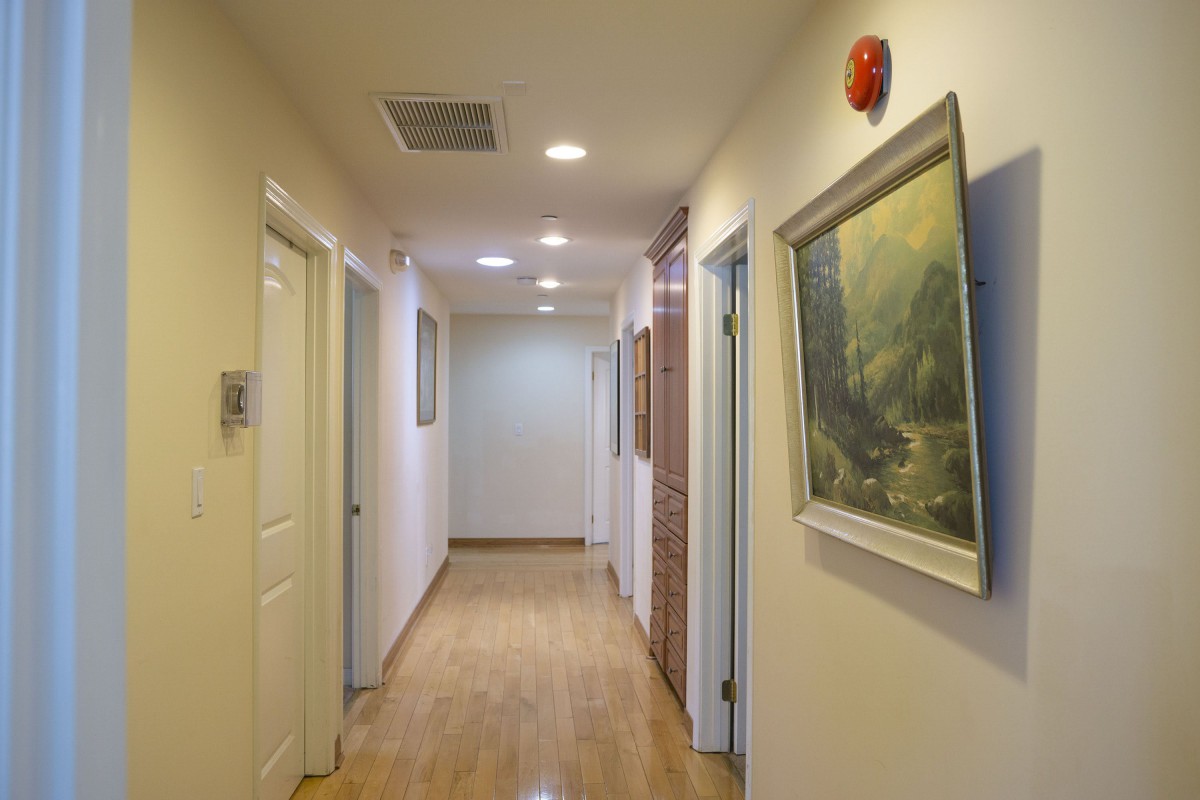 A well-lit hallway in an office with several doors and artwork on the walls.