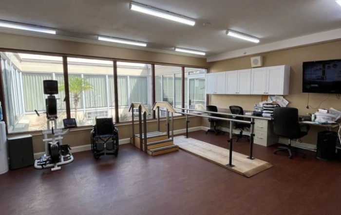 A physical therapy room equipped with parallel bars and medical equipment.