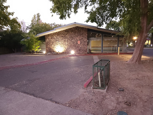 A modern stone-clad building illuminated by soft lights at dusk.