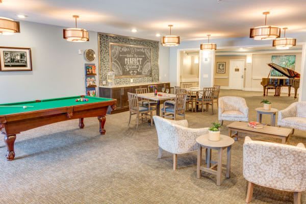A cozy recreation room featuring a billiards table and comfortable seating areas, with warm lighting enhancing the ambiance.