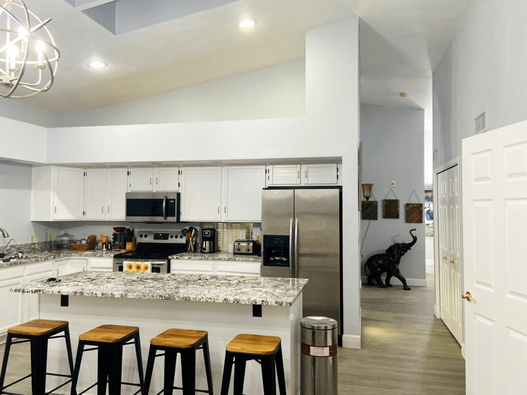 A modern kitchen with a central island and bar stools, featuring stainless steel appliances and sleek design elements.