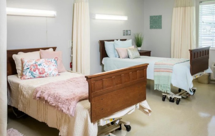 A clean and organized hospital room with two beds separated by a curtain, designed for patient care.
