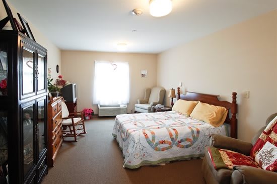 A cozy and well-furnished bedroom with a large bed, seating area, and natural light from the window.