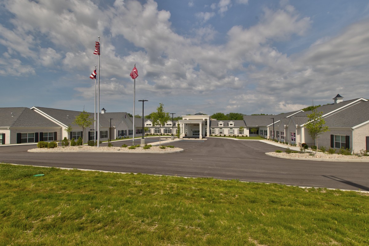 A modern building with flags flies in front and a well-maintained grassy area under a partly cloudy sky.