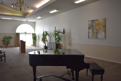 A grand piano positioned in a spacious hall, surrounded by lush plants and elegant decor.