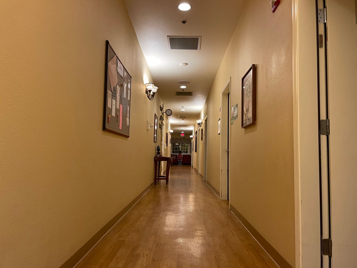 A long, warmly lit hallway with artwork on the walls and a wooden floor.