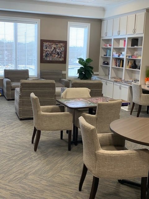 A cozy lounge area with comfortable chairs, tables, and a bookshelf.