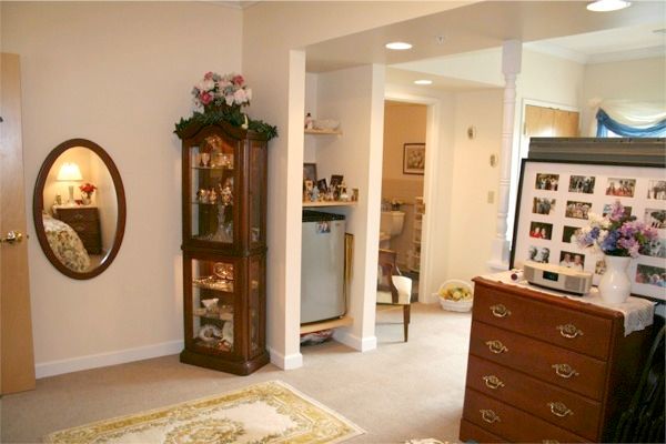 A cozy living room with elegant furniture and decor, featuring a cabinet, mirror, and wooden drawers.