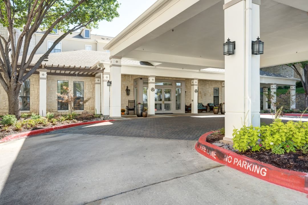 Front entrance of a building with a covered driveway and well-maintained landscaping.