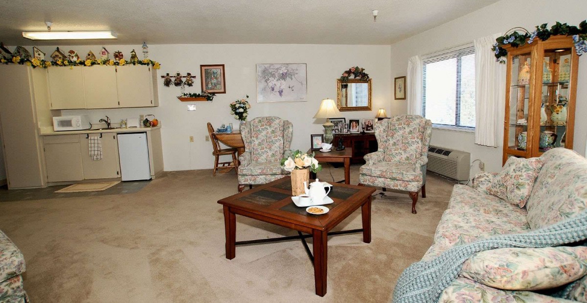 A cozy living room with comfortable chairs, a wooden coffee table, and homey decorations.