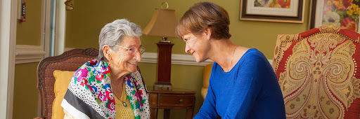 A heartwarming moment between an elderly woman and her caregiver, sharing smiles and connection.