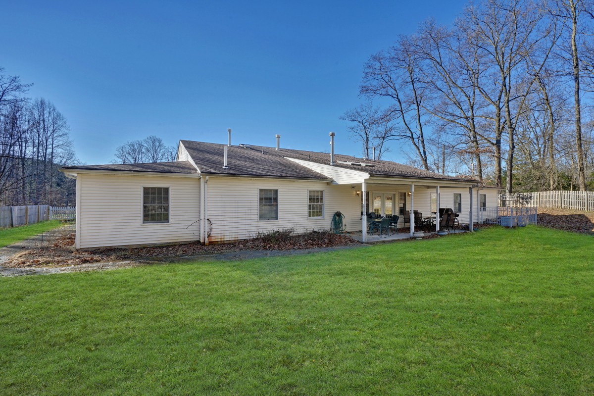 A view of a house with a spacious backyard and well-maintained lawn under a clear blue sky.