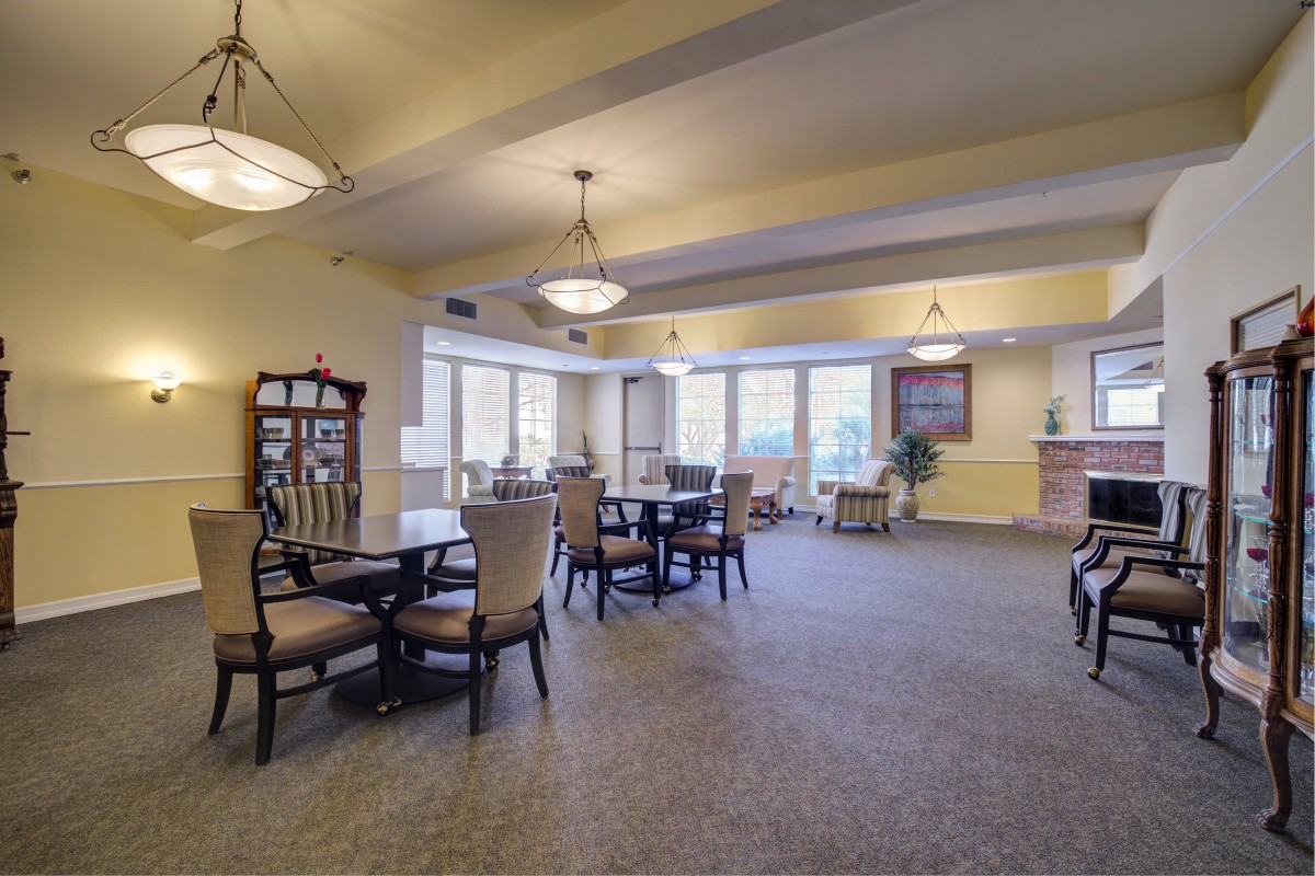 A spacious dining area with tables and chairs, featuring large windows and elegant lighting.