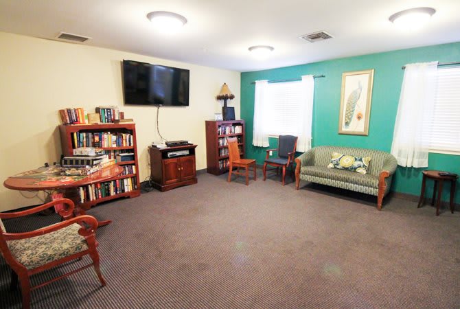 A cozy living room with a bookshelf, television, and comfortable seating.