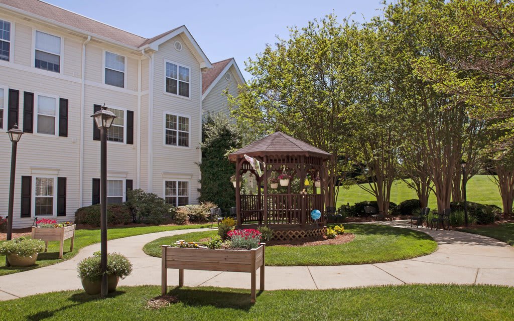 A peaceful garden with a gazebo beside a residential building.