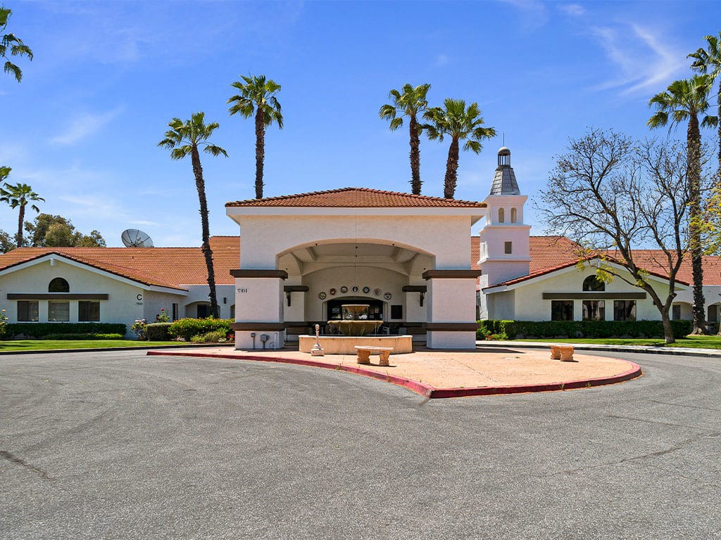 A bright day view of a building entrance with palm trees and clear blue sky.