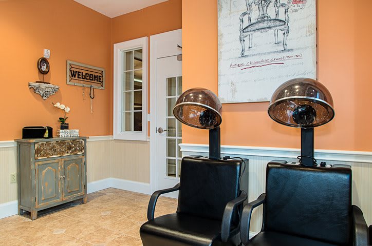 A cozy salon interior with vintage hair dryers and orange walls.