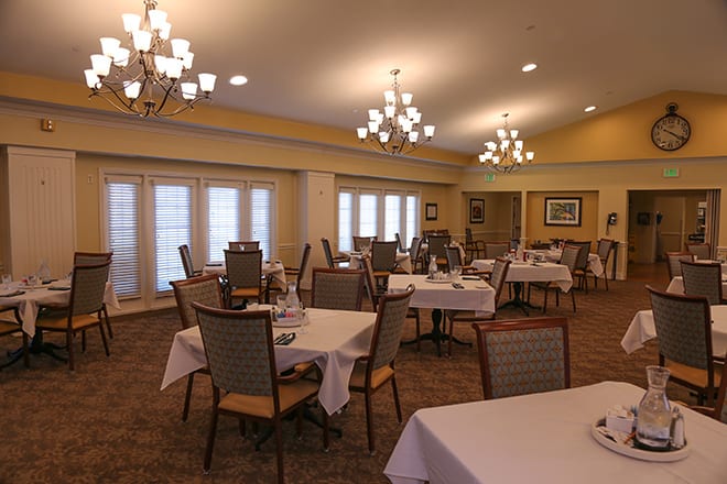 An elegantly set dining room with chandeliers and neatly arranged tables.