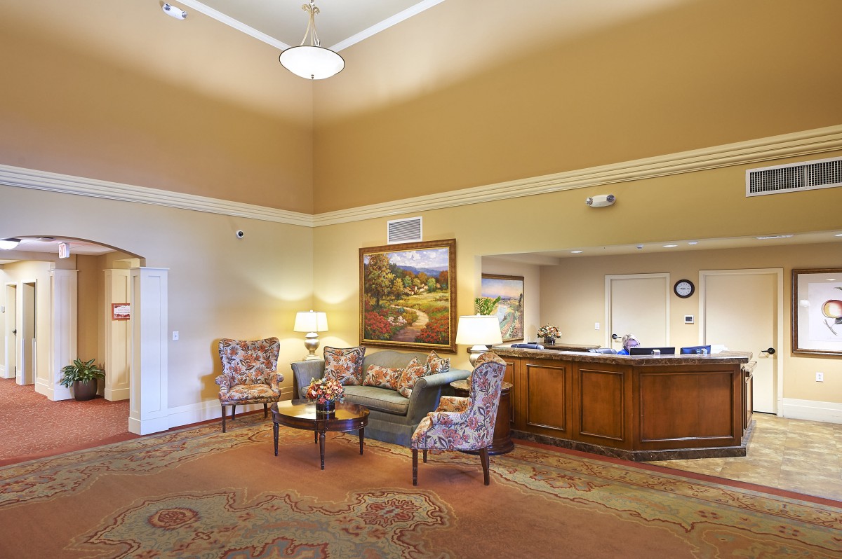 A spacious lobby with a reception desk, seating area, and decorative painting.