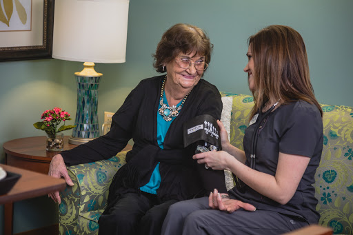 A healthcare professional conducts an interview with an elderly woman, both smiling and engaged in conversation.