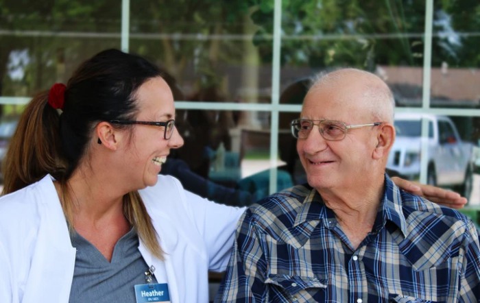 A caregiver and an elderly man share a moment of interaction and smiles.