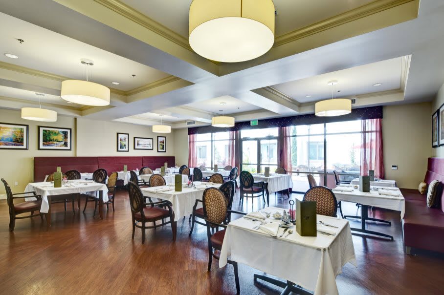 A spacious and elegantly decorated restaurant dining area with neatly set tables and ambient lighting.