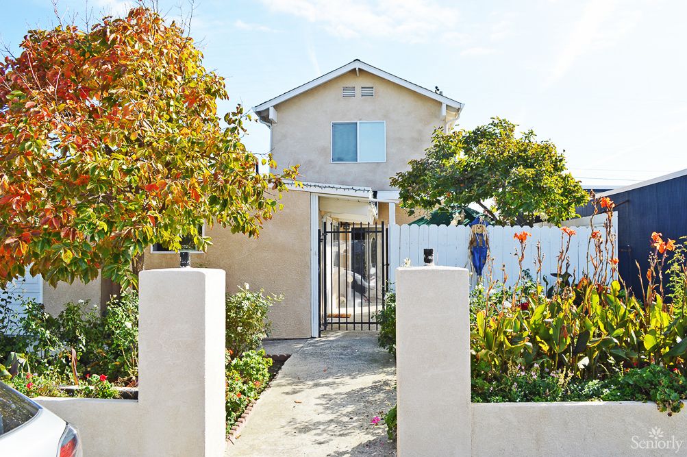 A two-story house with a garden and pathway leading to the entrance.