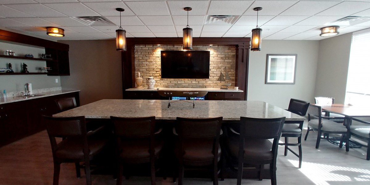 A stylish home bar setup featuring a marble countertop, pendant lights, and a brick accent wall with a mounted TV.