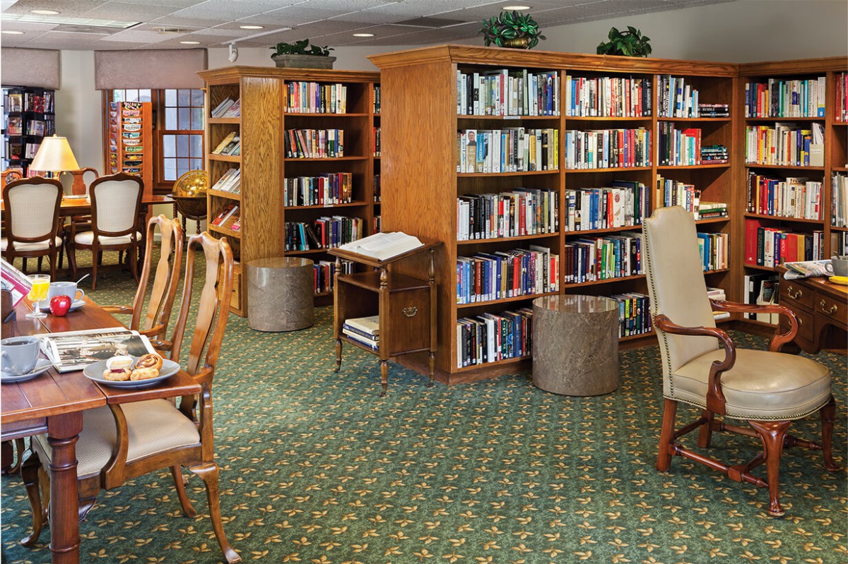 A cozy library setting with bookshelves, chairs, and a quiet reading area.
