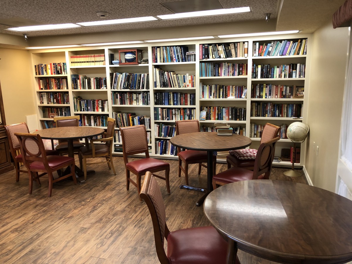 A cozy library study area with bookshelves, round tables, and chairs.