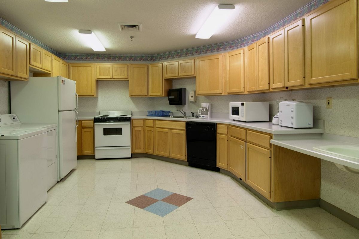 A spacious kitchen featuring light wood cabinets, modern appliances, and tiled flooring.