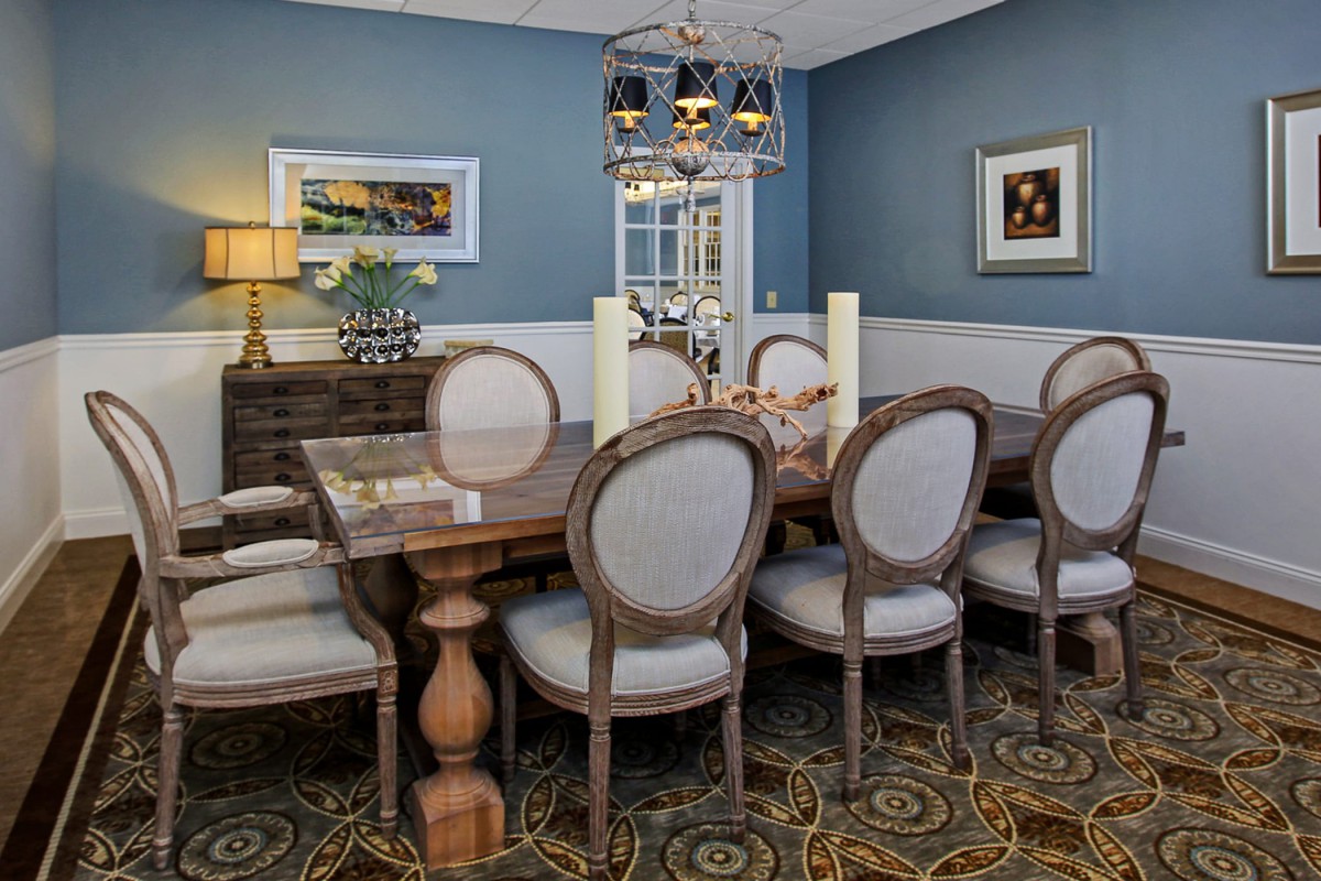 Elegant dining room with a wooden table and upholstered chairs, featuring classic decor and warm lighting.