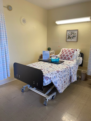 A clean and simple hospital room featuring an adjustable bed, medical supplies, and soft lighting.