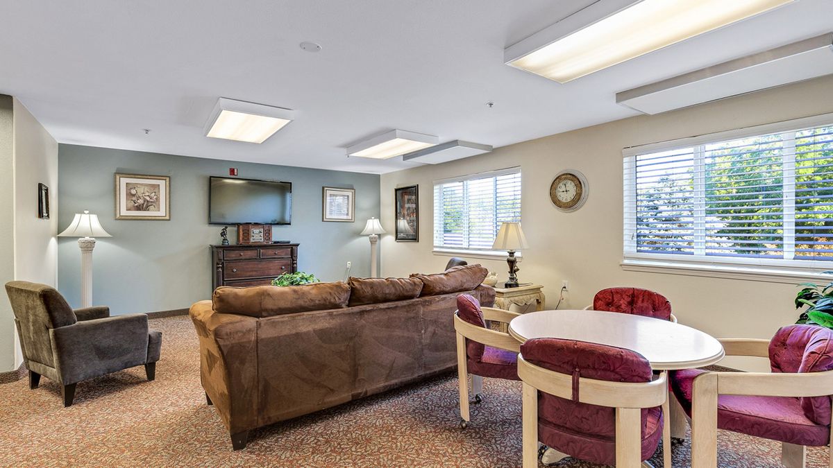 A cozy living room with a sofa, television, and a round table with chairs.