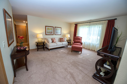 A cozy living room featuring a comfortable sofa and two armchairs, illuminated by natural light from large windows.